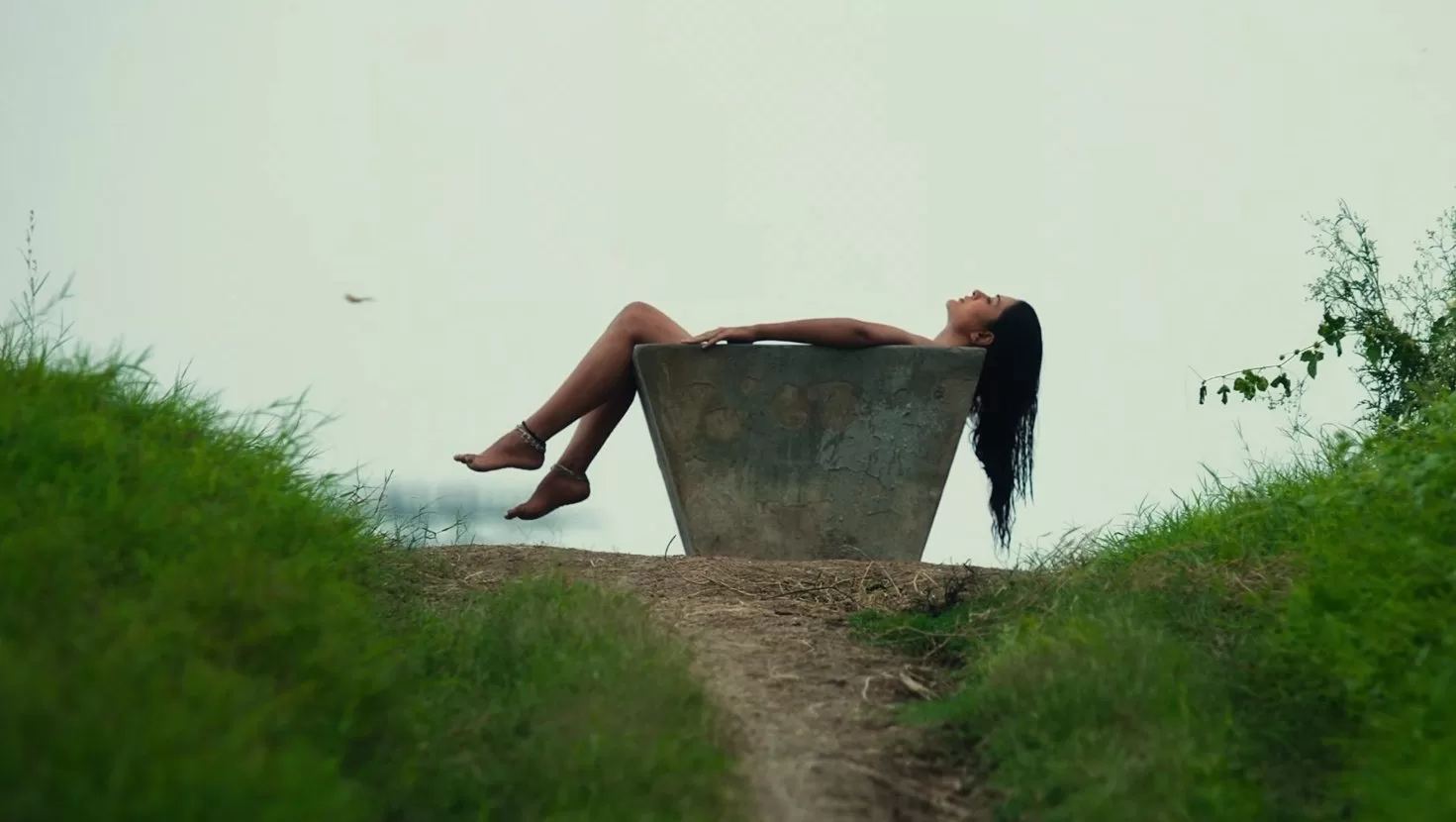 Image description: A scene from the latest Tollywood release Mangalvaaram showing Paayal Rajput in an eerie background. She lays apparently naked in a rusty steel tub amidst a field, starring Payal Rajput, the trending actress on X.